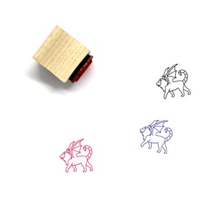 May include: A wooden rubber stamp with a red ink pad. The stamp features a line drawing of a winged lion, a mythical creature.