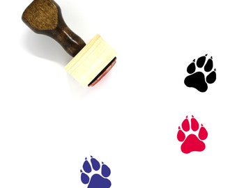 Puede incluir: Un sello de goma de madera con un diseño de huella de pata. El sello se muestra con tres huellas de pata de diferentes colores: negro, rojo y azul.
