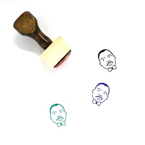 May include: A wooden rubber stamp with a black and white illustration of a man's face with a bow tie. The stamp is on a white background.