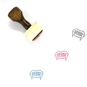 May include: A wooden rubber stamp with a red ink pad. The stamp features a black line drawing of a set of vampire fangs.