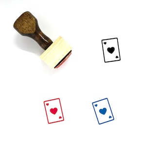 Puede incluir: Un sello de madera con un mango y una base rectangular. El sello presenta un contorno negro de una carta de juego con un símbolo de corazón. El sello se muestra con tres impresiones de tinta de diferentes colores: negro, rojo y azul.