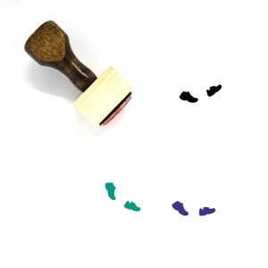 Puede incluir: Un sello de madera con mango y una almohadilla de tinta rectangular. El sello se utiliza para crear huellas de zapatos. La imagen muestra el sello y varias huellas de diferentes colores.