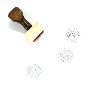 Puede incluir: Un sello de madera con un mango marrón y una base rectangular. El sello está diseñado para crear un patrón de pequeños puntos en forma circular. El sello se muestra con tres impresiones del patrón en negro, rojo y azul.