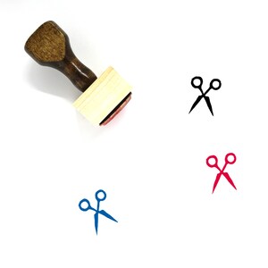 May include: A wooden stamp with a handle and a square base. The stamp features a black silhouette of a pair of scissors. The stamp is shown on a white background.