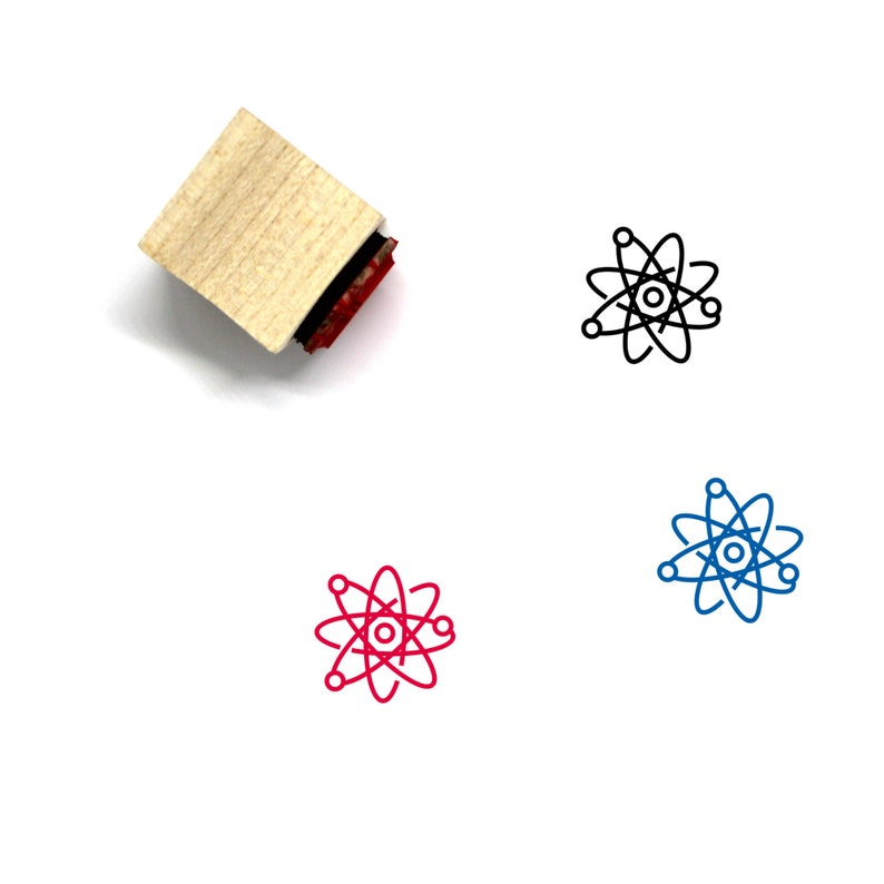 Puede incluir: Un sello de madera con una almohadilla de tinta roja. El sello presenta un dibujo de l&iacute;nea en blanco y negro de un &aacute;tomo con un n&uacute;cleo y electrones en &oacute;rbita. El &aacute;tomo tambi&eacute;n se muestra en rojo y azul.