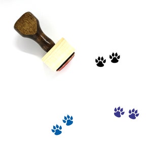 May include: A wooden stamp with a brown handle and a rectangular wooden block. The stamp features two black paw prints. There are also two blue paw prints below the stamp.