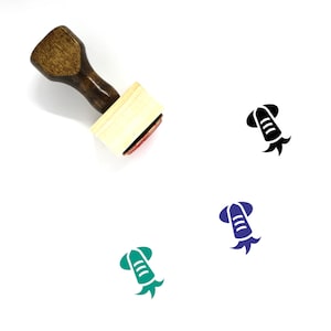 May include: A wooden rubber stamp with a brown handle and a rectangular base. The stamp features a green silhouette of a squid with a single eye.
