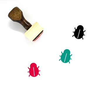 Puede incluir: Un sello de madera con un diseño de insecto negro, verde y rojo. El insecto tiene una línea blanca en el medio de su cuerpo.