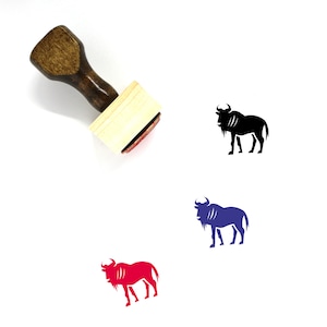 Peut inclure: Un tampon en caoutchouc en bois avec un tampon d'encre noir. Le tampon présente une silhouette noire d'une gnou. Le tampon est présenté à côté de trois silhouettes de gnou de couleurs différentes : noir, bleu et rouge.