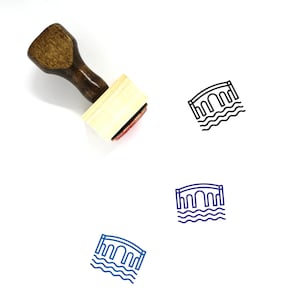 Puede incluir: Un sello de madera con un diseño de puente. El sello tiene una base de madera clara y un mango marrón oscuro. El diseño del puente se repite en tinta negra y azul.