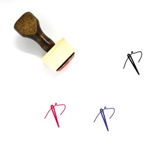 May include: Wooden stamp with a brown handle and a rectangular wooden block. The stamp is designed to create an image of a needle and thread.