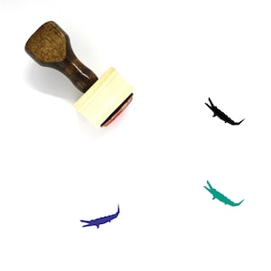 Puede incluir: Sellos de goma de madera con un diseño de silueta de cocodrilo. El sello es marrón con una base de madera clara. El cocodrilo se muestra en negro, verde y azul.