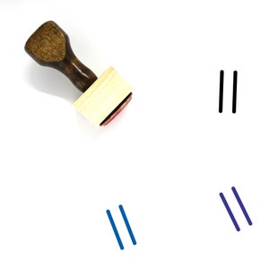 May include: A wooden stamp with a brown handle and a rectangular wooden block. The stamp is used to create parallel lines. The image shows the stamp and three examples of the lines it creates: black, blue, and dark blue.