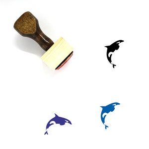May include: A wooden stamp with a brown handle and a rectangular base. The stamp's imprint features a black and white orca whale design. Additional orca whale designs in blue and black are also shown.