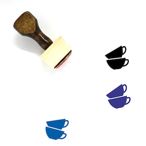 May include: A wooden rubber stamp with a handle and a rectangular base. The stamp features a design of two stacked teacups, one blue and one dark blue.