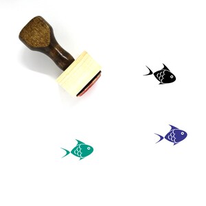 Peut inclure: Un tampon en caoutchouc en bois avec un motif de poisson. Le tampon est sur un fond blanc. Le poisson est noir, vert et bleu.