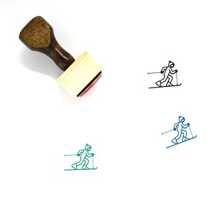 以下が含まれることがあります： 赤いインクパッドが付いた木製スタンプ。スタンプには、スキーをしている人の黒の線画が描かれています。