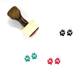 May include: A wooden stamp with a red ink pad. The stamp features a paw print design. There are three sets of paw prints in the image, one set is black, one set is green, and one set is red.