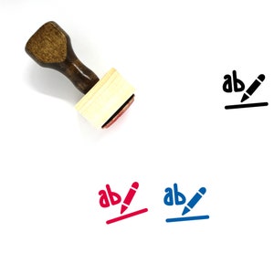 May include: A wooden rubber stamp with a black ink pad. The stamp features the letters "ab" with a pencil drawn through them and a line underneath. The stamp is shown next to three versions of the stamp imprint in black, red, and blue.