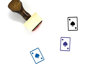 May include: A wooden rubber stamp with a brown handle and a rectangular wooden base. The stamp features a black and white illustration of a playing card with the ace of spades.
