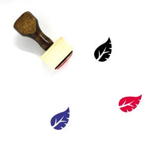 May include: A wooden rubber stamp with a brown handle and a rectangular wooden block. The stamp features a black leaf design. The image also shows the leaf design in blue, red, and black.