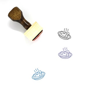 May include: A wooden rubber stamp with a handle and a rectangular base. The stamp features a line drawing of a plate of steaming cheese.