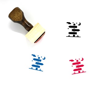 May include: A wooden rubber stamp with a design of a signpost with three arrows pointing in different directions. The signpost is surrounded by stars and a crescent moon. The stamp is red and black.