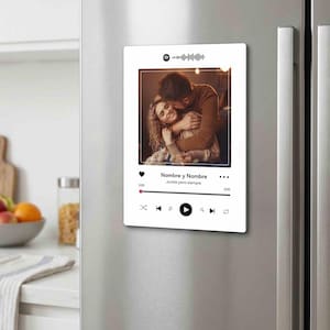 May include: A rectangular white magnet featuring a custom photo of two people embracing. The design mimics a music player interface with a Spotify code at the top, the text "Nombre y Nombre" and "Juntos para siempre," and playback control icons.