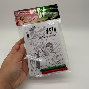 May include: A clear plastic bag containing a colouring book and two crayons. The colouring book has a black and white illustration of two women and the text "A WICKED #5TH birthday party!". The bag also has a header with the text "mia 5# is turning".