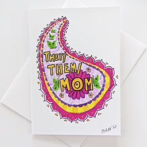 May include: A pink, yellow, and green paisley-shaped card with the text "They/Them/Mom" inside. The card is decorated with small green figures and a pink flower.