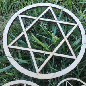 May include: A wooden circle with a six-pointed star design cut out of the center. The star is made up of overlapping triangles.