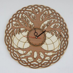 Peut inclure: Une horloge murale en bois avec un motif d'arbre de vie. Le cadran de l'horloge est un cercle avec un fond blanc et des aiguilles noires. L'arbre de vie est finement sculpté avec des branches et des feuilles.