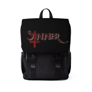Peut inclure: Sac à dos noir avec le mot "SINNER" en script rouge et un symbole de croix rouge. Le sac à dos a une fermeture à rabat avec deux sangles à boucle et une poignée supérieure. Des coutures blanches ornent les bords.
