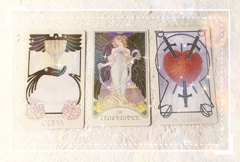 Puede incluir: Tres cartas de tarot, el As de Copas, la Templanza y el Tres de Espadas. La carta del As de Copas presenta una copa dorada con una mano que se extiende hacia ella. La carta de la Templanza muestra a una mujer vertiendo agua de una copa a otra. La carta del Tres de Espadas muestra tres espadas que perforan un coraz&oacute;n.