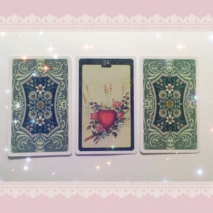 May include: Three tarot cards with ornate green and blue borders. The card on the left has a number "0" in the center. The card in the middle has the number "24" in the center and a red heart with flowers. The card on the right has a number "0" in the center.