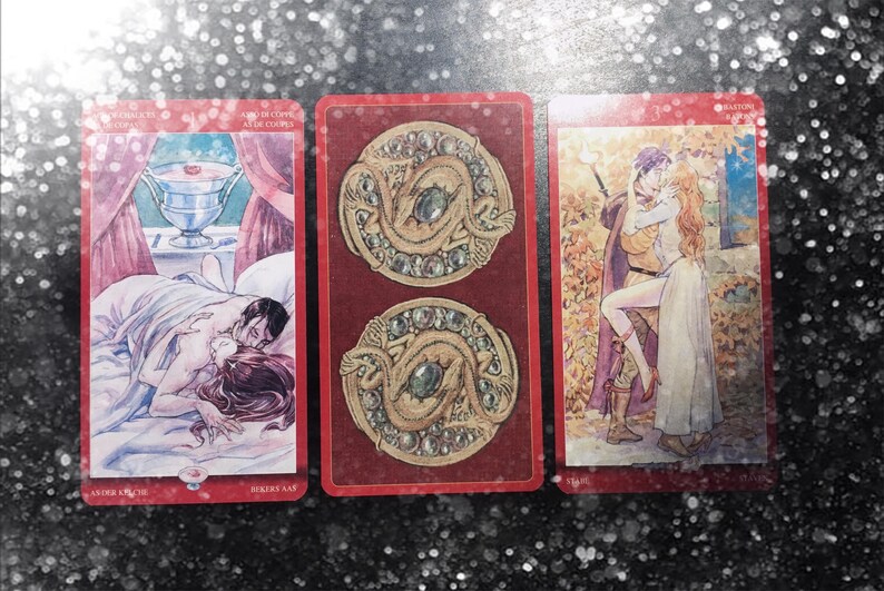 May include: Three rectangular tarot cards with red borders. The left card shows a couple embracing in bed with a silver chalice above. The center card features two circular gold medallions with dragons and green gems. The right card depicts a couple kissing.