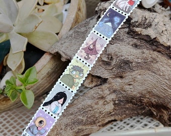 May include: A roll of washi tape featuring a repeating pattern of colourful illustrations of animals and mythical creatures. Each illustration is framed with a white border and a dotted line.