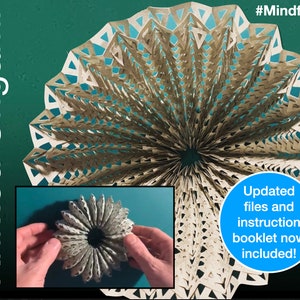 May include: A white paper origami sculpture with a geometric pattern. The sculpture is folded into a circular shape with a hole in the centre. The sculpture is on a green background. The text "Knitted Origami" is on the left side of the image. The text "#Mindfulness" is on the right side of the image. The text "Updated files and instruction booklet now included!" is in a blue circle on the bottom right side of the image.