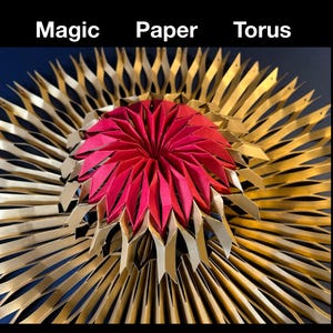 Puede incluir: Una escultura de papel circular titulada Magic Paper Torus con un grupo central de pétalos geométricos rojos plegados, rodeado por un amplio anillo radiante de segmentos de papel dorado metálico, puntiagudos y plisados.