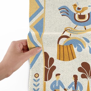 May include: Close-up of a patterned fabric with a folk art design. The design features a blue bird, a wooden bucket, and figures in blue clothing. The fabric has a cream background with blue, yellow, and brown accents.