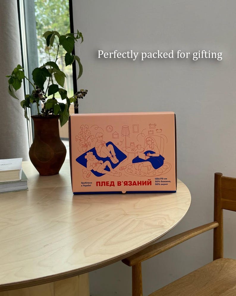 May include: A peach-colored gift box with a blue illustration of people relaxing indoors. The box has text in Ukrainian and English, and the words "Perfectly packed for gifting" are above the box.