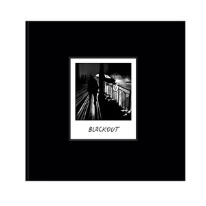 Pode incluir: Fotografia a preto e branco de uma pessoa a caminhar numa rua &agrave; noite. A pessoa est&aacute; em silhueta contra um candeeiro de rua. A imagem &eacute; enquadrada numa moldura branca com a palavra "BLACKOUT" impressa abaixo da imagem.