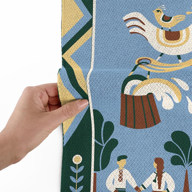 May include: A section of a blue fabric with a folk art design. The design includes a large white bird with a smaller bird on its back, a brown bucket, and figures in traditional clothing. The fabric has yellow, green, and white accents.