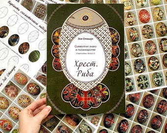 May include: A green book with a fish design on the cover. The book title is "Хрест. Риба" and the author is "Зоя Сташук". The book is about symbolic signs in Ukrainian pysanka art.