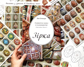 May include: A book titled "Symbolic Signs in Pysanky" by Zoya Stashuk. The book cover features a colourful pysanky egg with geometric patterns in red, yellow, black, and white. The book is part of a series titled "Zirkia".