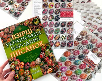 May include: A selection of vibrantly decorated Easter eggs and printed materials. The image shows a book with Ukrainian text and sheets displaying egg designs. The eggs feature intricate patterns in red, yellow, green, and black.