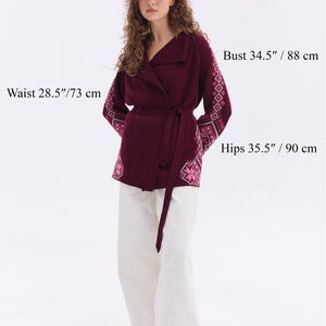 May include: A burgundy wrap sweater with embroidered sleeves and a matching belt. The model's measurements are: height 5'8"/172 cm, bust 34.5"/88 cm, waist 28.5"/73 cm, and hips 35.5"/90 cm. The sweater is one size, fitting US sizes 8-12.