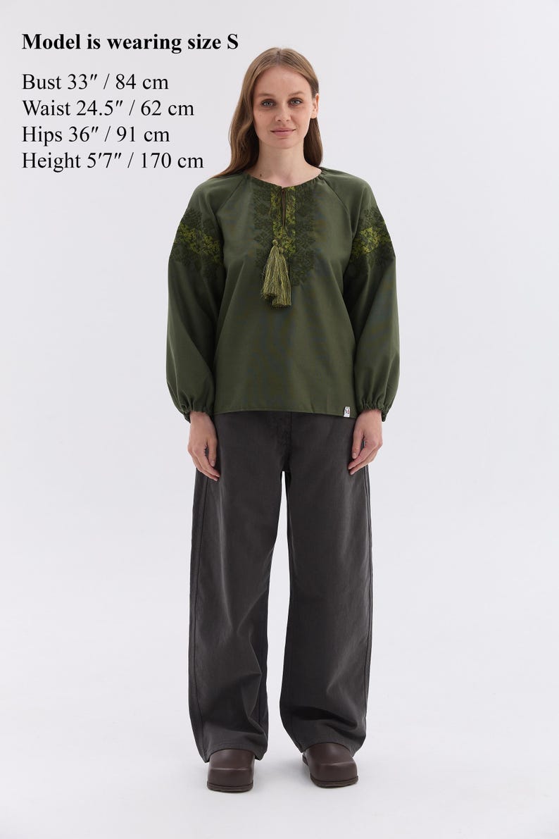 May include: An olive green blouse with embroidered details and a tassel, paired with dark gray wide-leg pants. The model is wearing size S. Bust 33 inches, waist 24.5 inches, hips 36 inches, and height 5'7 inches.