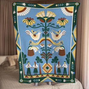 May include: A blue blanket with a folk art design. The blanket features white birds, yellow flowers, and figures in traditional clothing. The border is green with white and yellow accents. The blanket is displayed on a bed.