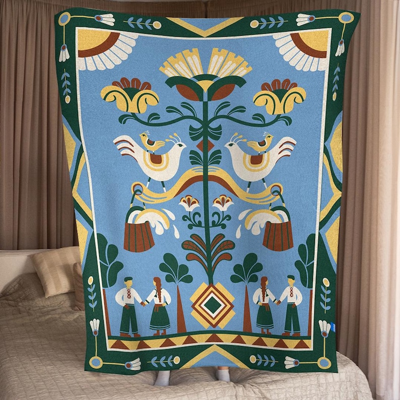 May include: A blue blanket with a folk art design. The blanket features white birds, yellow flowers, and figures in traditional clothing. The border is green with white and yellow accents. The blanket is displayed on a bed.